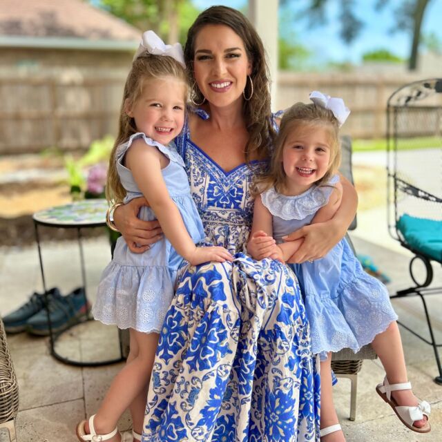 A woman smiling with two young girls outdoors